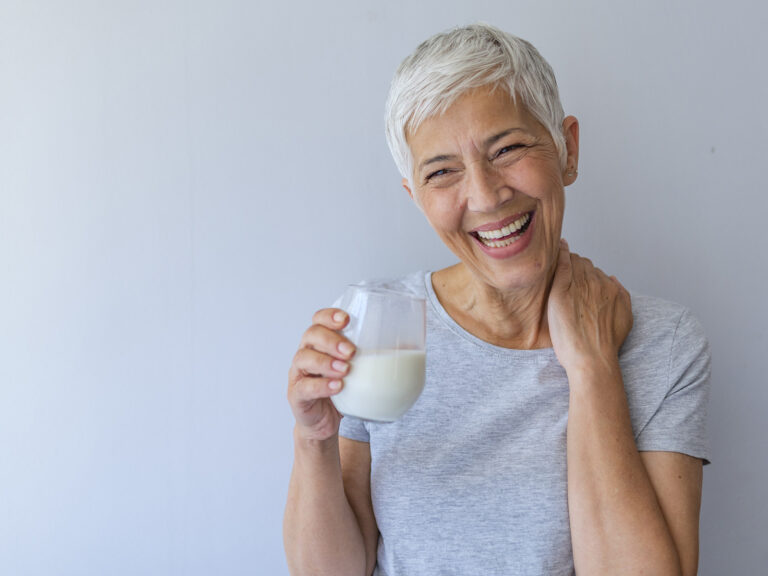 Mujer mayor sonriente sosteniendo vaso de leche